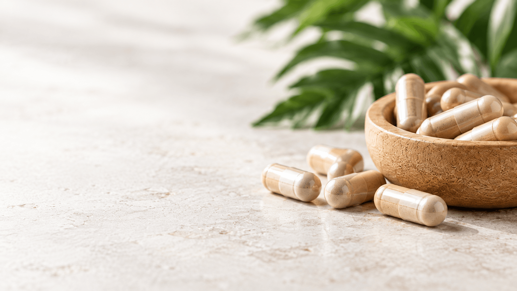 Beige capsules beside a wooden bowl on a stone tabletop