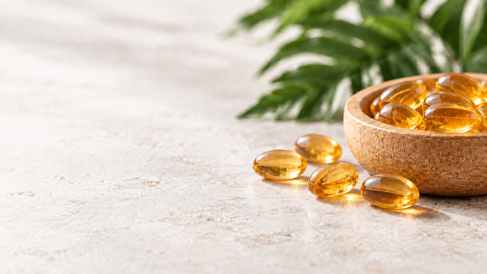 Golden supplement softgels in a wooden bowl on a stone tabletop